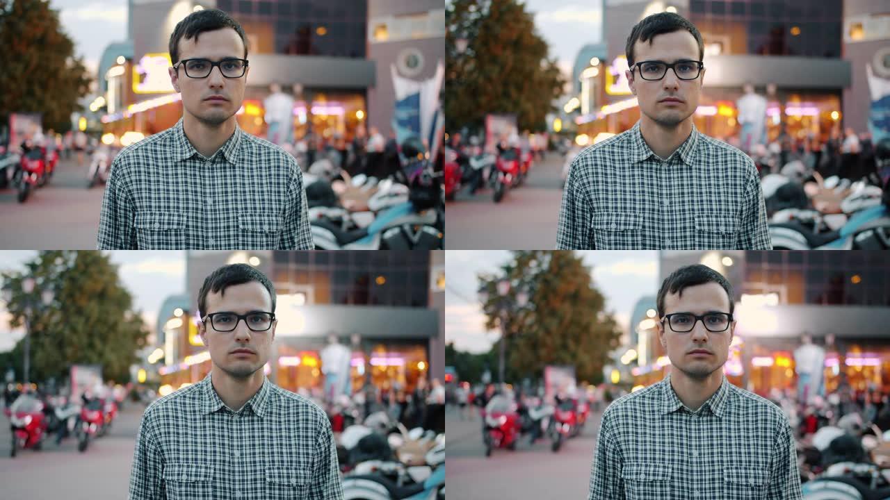 严肃的年轻商人戴着眼镜的慢动作独自站在城市街道上