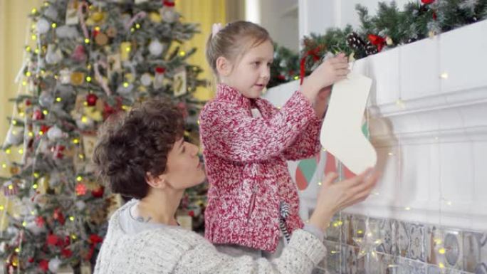 小女孩在妈妈和哥哥的帮助下为圣诞节装饰家