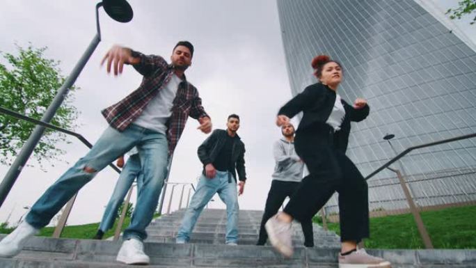 一群不同种族的年轻城市舞者的慢动作很高兴在摩天大楼的市中心进行训练