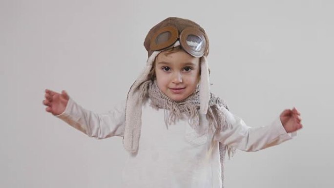 一个女孩的肖像，打扮成飞行员或飞行员，戴着帽子和眼镜，微笑着看着相机，她睁着眼睛做梦，想着未来。