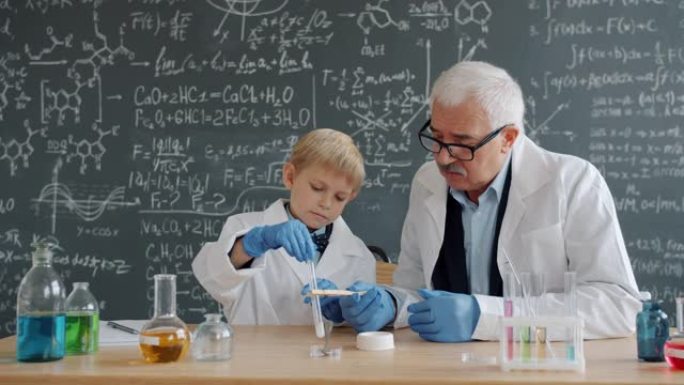 在化学课上进行实验的聪明男孩和成熟老师的慢动作