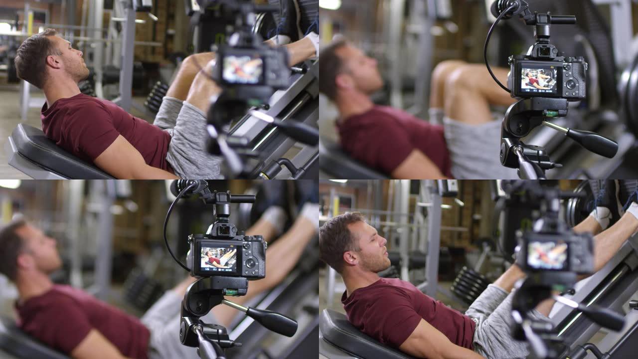 健身房教练在相机上展示腿部按压运动