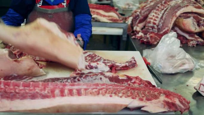 植物工人正在雕刻大块带骨的肉。食品生产、肉类、猪肉加工厂。