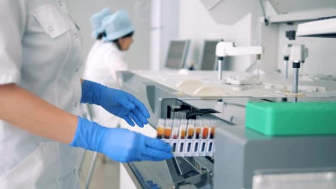 实验室工作人员将装有血液样本的架子放入现代自动化医疗设备中。