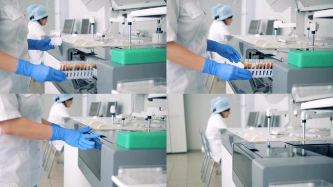 实验室工作人员将装有血液样本的架子放入现代自动化医疗设备中。