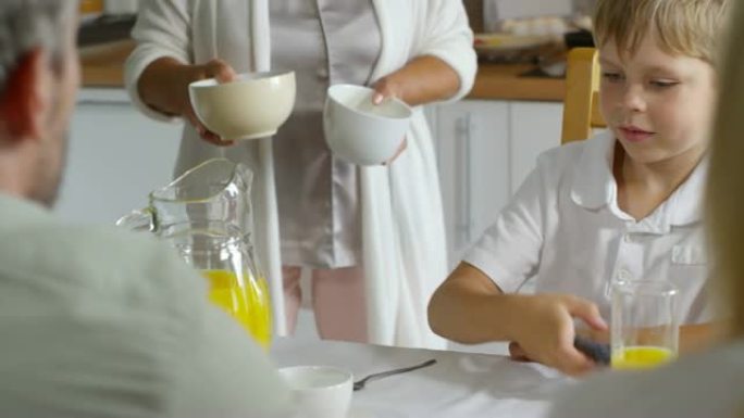 小男孩在家庭早餐时打开电视