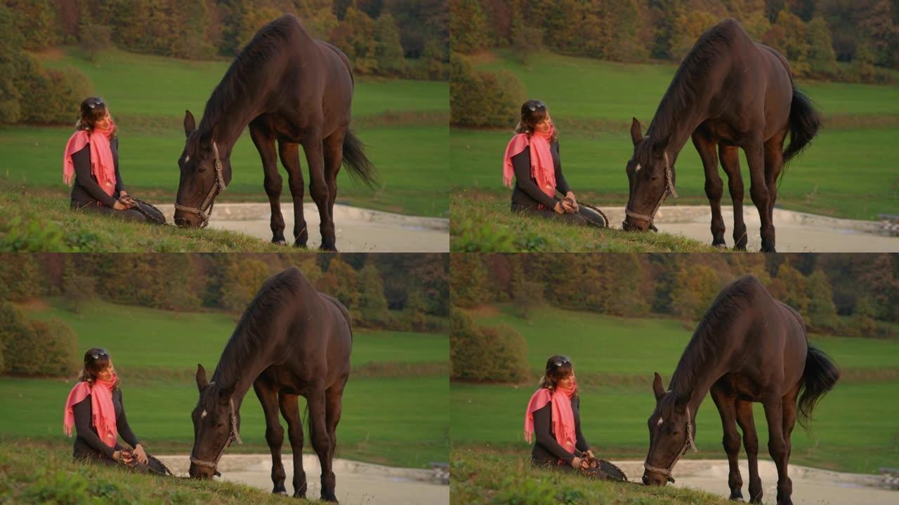 慢动作: 快乐的女孩坐着，看着她的马在宁静的田野里吃草。