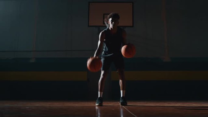 一名年轻职业男球员的电影慢动作镜头正在健身房用两个球练习篮球锻炼
