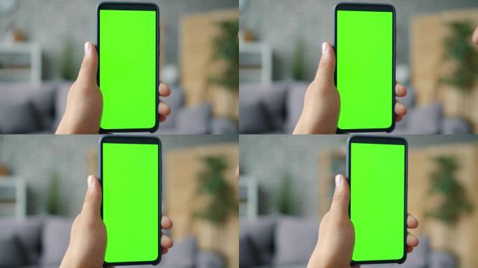 公寓中男性手持色度键绿屏智能手机的特写