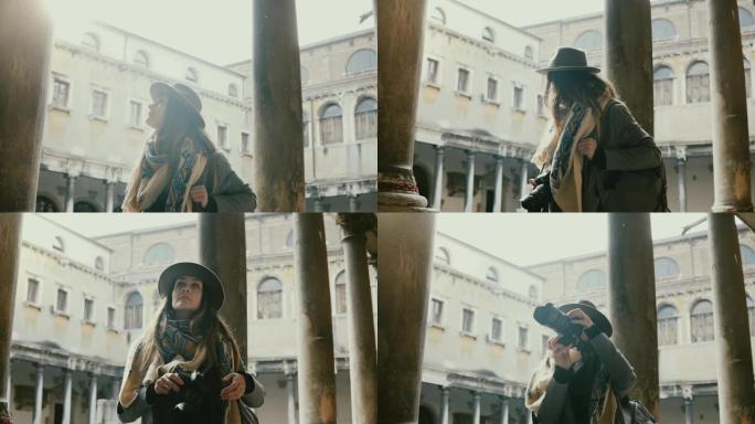 美丽的女性专业摄影师用相机在威尼斯老城的古建筑柱子上拍照。