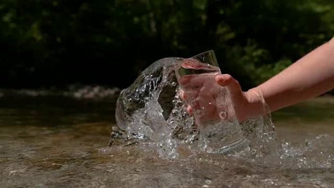 慢动作: 不知名的人拿着透明的玻璃杯，舀起纯净水。