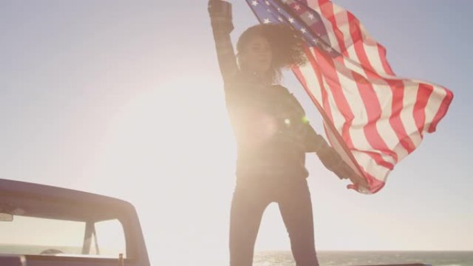 女人站在4k皮卡车上挥舞着美国国旗