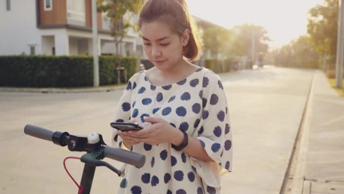 年轻女子用手机解锁电动推动踏板车