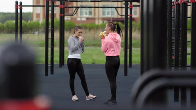 高加索双胞胎姐妹在户外健身房吃零食
