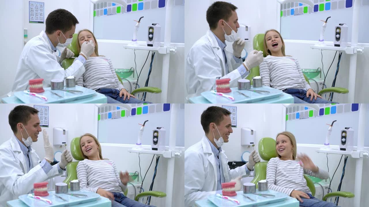 友好的牙医在检查牙齿后向一个高五岁的年轻女孩表示祝贺