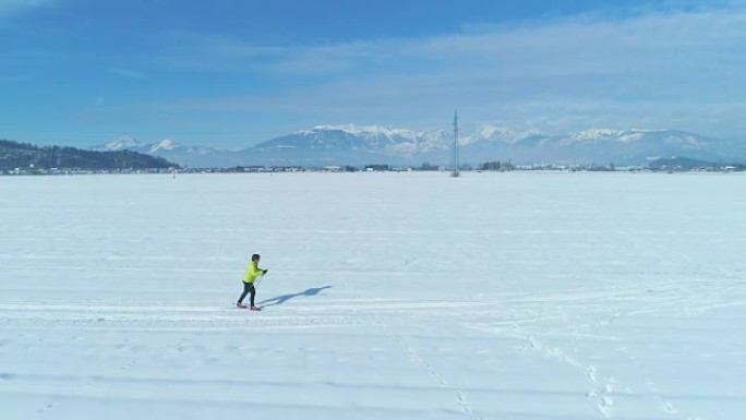空中: 沿着一名活跃的妇女在斯洛文尼亚广阔的白雪皑皑的平原上滑雪。