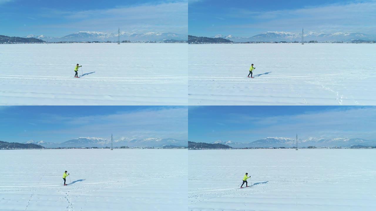 空中: 沿着一名活跃的妇女在斯洛文尼亚广阔的白雪皑皑的平原上滑雪。