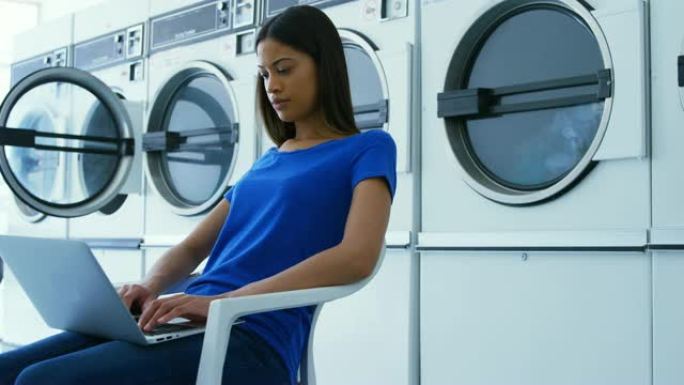 在4k自助洗衣店使用笔记本电脑的女人