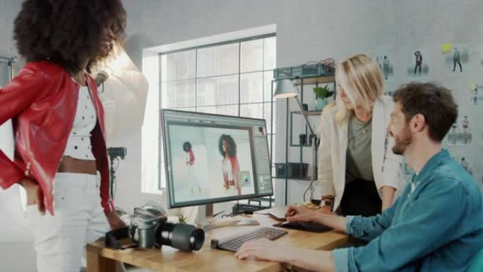 在照相馆时尚杂志设计师和美丽的黑色封面女孩与专业摄影师交谈，后者使用台式计算机在图像编辑软件中修饰照