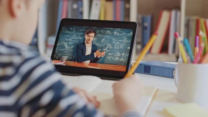 聪明的小男孩使用数字平板电脑与老师进行视频通话。屏幕显示在线讲座，老师从教室讲解主题。电子教育远程学