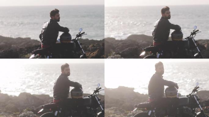 英俊的男人坐在海边的经典摩托车上