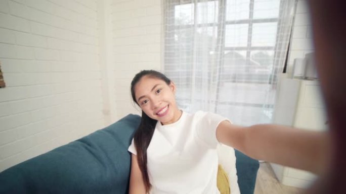 年轻的亚洲青少年妇女在家中vlog，女性使用智能手机在客厅的社交媒体上制作vlog视频。生活方式女人