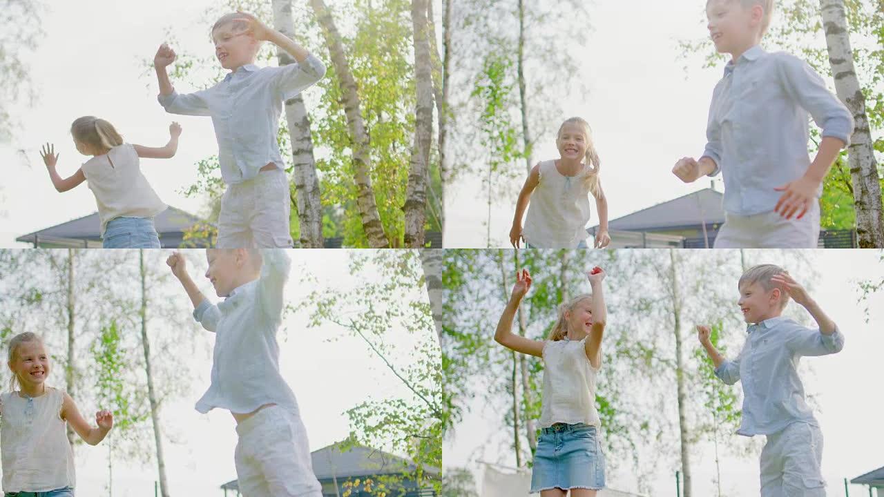 可爱的小男孩和女孩在蹦床上跳来跳去的低角度镜头。孩子们在后院玩耍。慢动作。