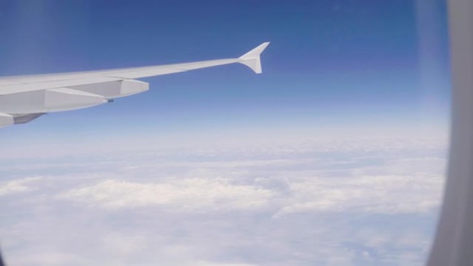 从飞机内部可以看到白云和飞机机翼的天空。