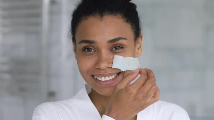 快乐的非洲裔美国妇女使用鼻子清洁条。