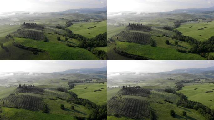 经典的托斯卡纳景观。飞越意大利托斯卡纳 (托斯卡纳) 的绿色山丘，布满薄雾和云彩。单别墅也可以在镜头