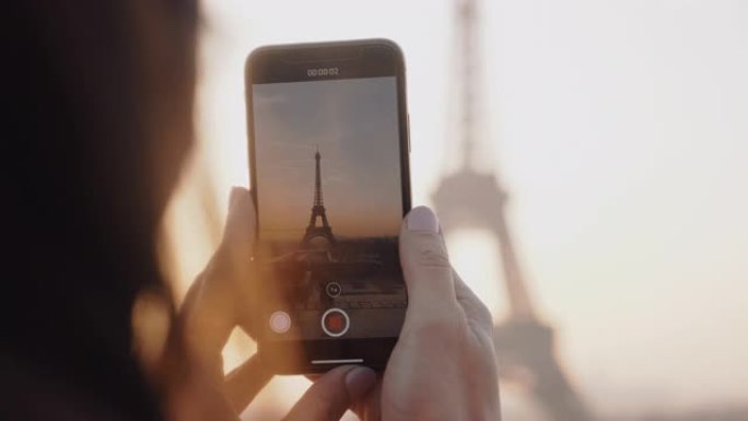 特写快乐当地博客女人用手机慢镜头拍摄史诗般的日落巴黎埃菲尔铁塔天空全景视频。