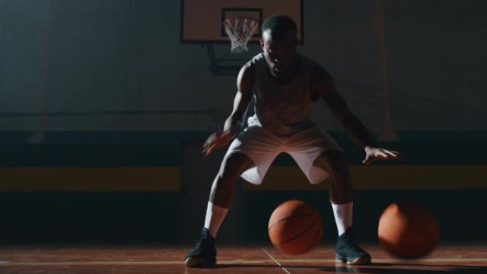 一名年轻的非洲职业男球员的电影慢动作镜头正在健身房用两个球练习篮球锻炼