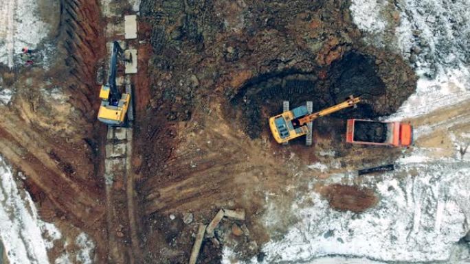 采石场用沙子工作的建筑机械。挖掘机和卡车工作的建筑工地上方的鸟瞰图。