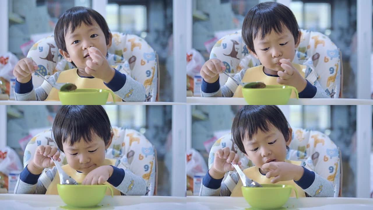亚洲男婴在高脚椅上吃胡萝卜。