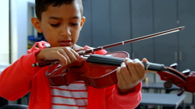 细心的亚洲男生在学校4k教室拉小提琴的前视图