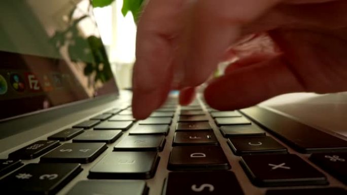 有人在笔记本电脑的键盘上打字，按下按钮进行在线交流，编码和编程软件，在家工作。UHD滑块镜头