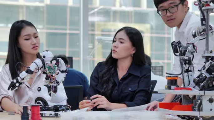 小组青少年在学校机器人俱乐部项目的功能齐全的可编程机器人上工作。创意设计师在车间测试机器人原型。教育