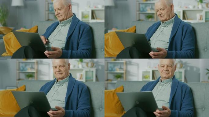 坐在沙发上的进步高级男子在家中使用笔记本电脑。充满生活的老人在家放松，在互联网上阅读新闻。