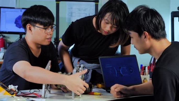 工程专业的学生在实验室工作，一个学生正在实验室调整3D打印机的组件。他们在CAD程序中设计新的组件。