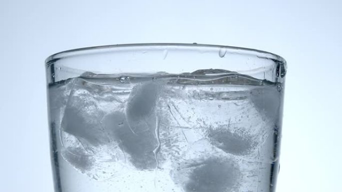 将新鲜和干净的水和冰块倒入玻璃杯的慢动作