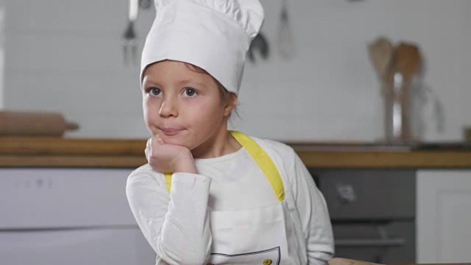 一个小女孩在厨房里打扮成专业厨师的肖像。