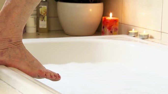 高级妇女的脚在浴缸边缘。
