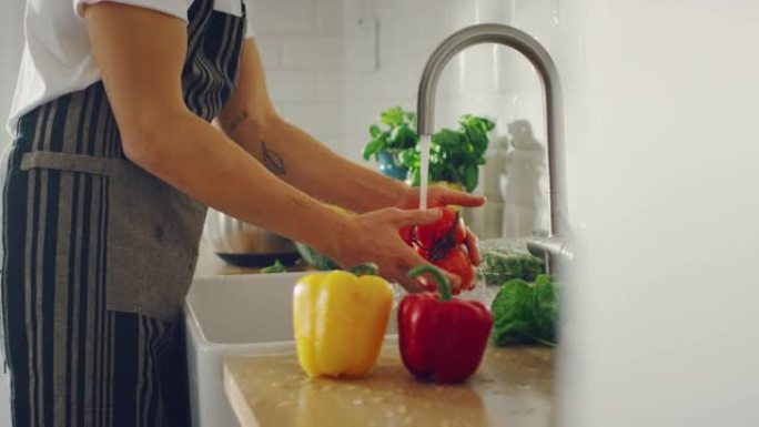 慢动作特写一名男子用自来水洗西红柿的镜头。正宗的时尚厨房配健康蔬菜。有机农业手工清洗的天然清洁产品。
