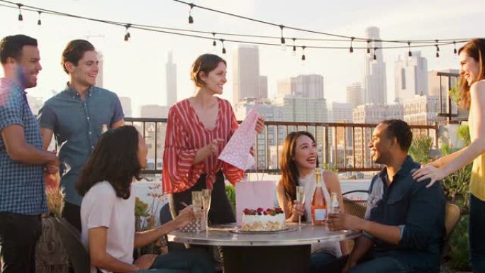 朋友聚集在屋顶露台上，以城市天际线为背景庆祝生日