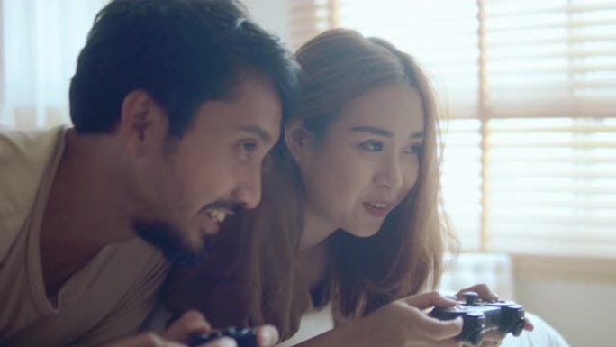 亚洲夫妇在家里的卧室里玩电子游戏。