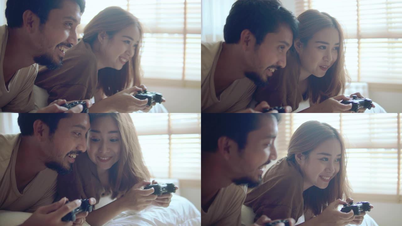 亚洲夫妇在家里的卧室里玩电子游戏。