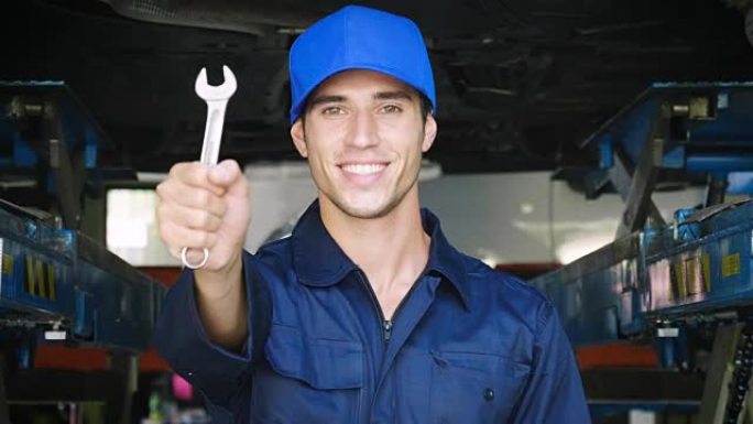 在汽车维修车库中，一名机械师在安顿好汽车后将钥匙显示为汽车准备启动。
