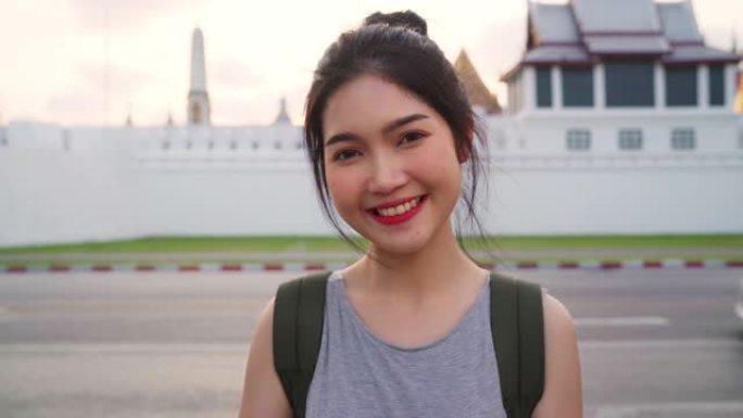 在泰国曼谷，背包客亚洲女性在传统城市令人惊叹的地标上享受他们的旅程。看着相机的肖像。