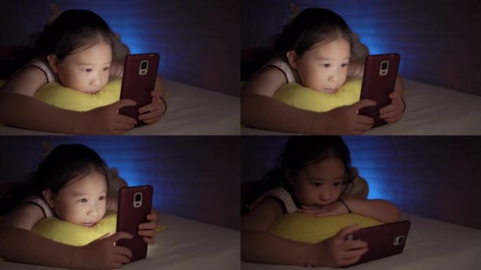 可爱的小女孩在卧室里使用智能手机