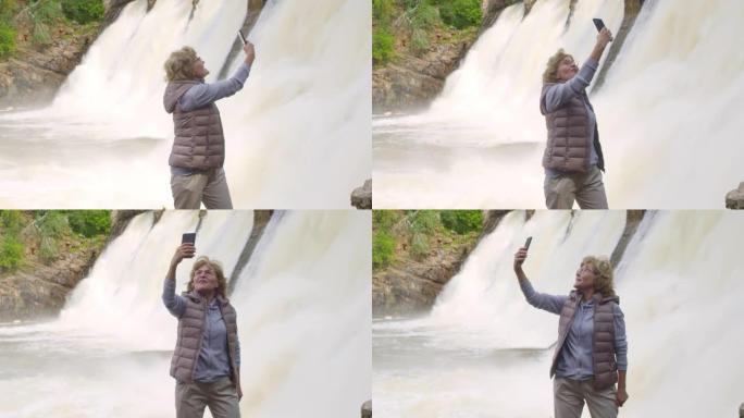 快乐的老年妇女在溢洪道前拍摄自己